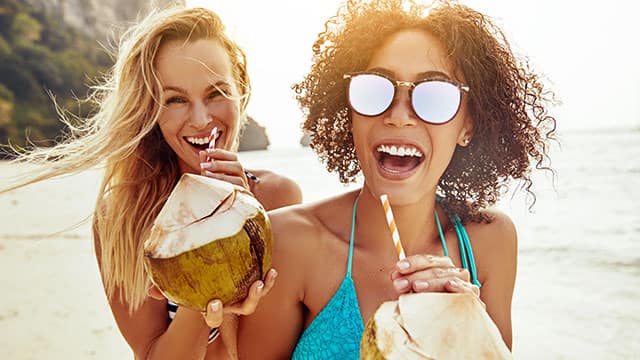 two friends drinking from coconuts